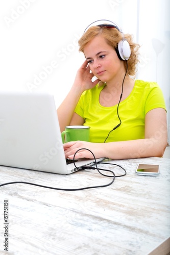 Young plus size woman listening to Audio while working on a laptop