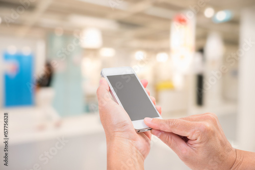 Hands holding mobile phone with blurred image of shopping mall