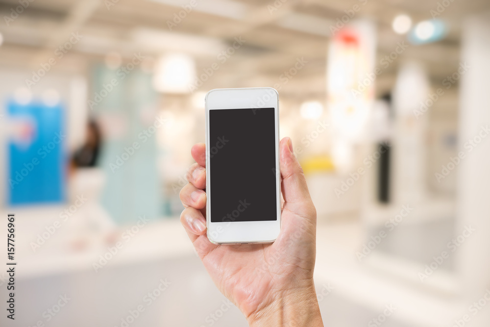 Hand holding empty screen mobile phone with abstract blurred interior background Hand holding empty screen mobile phone with abstract blurred interior background
