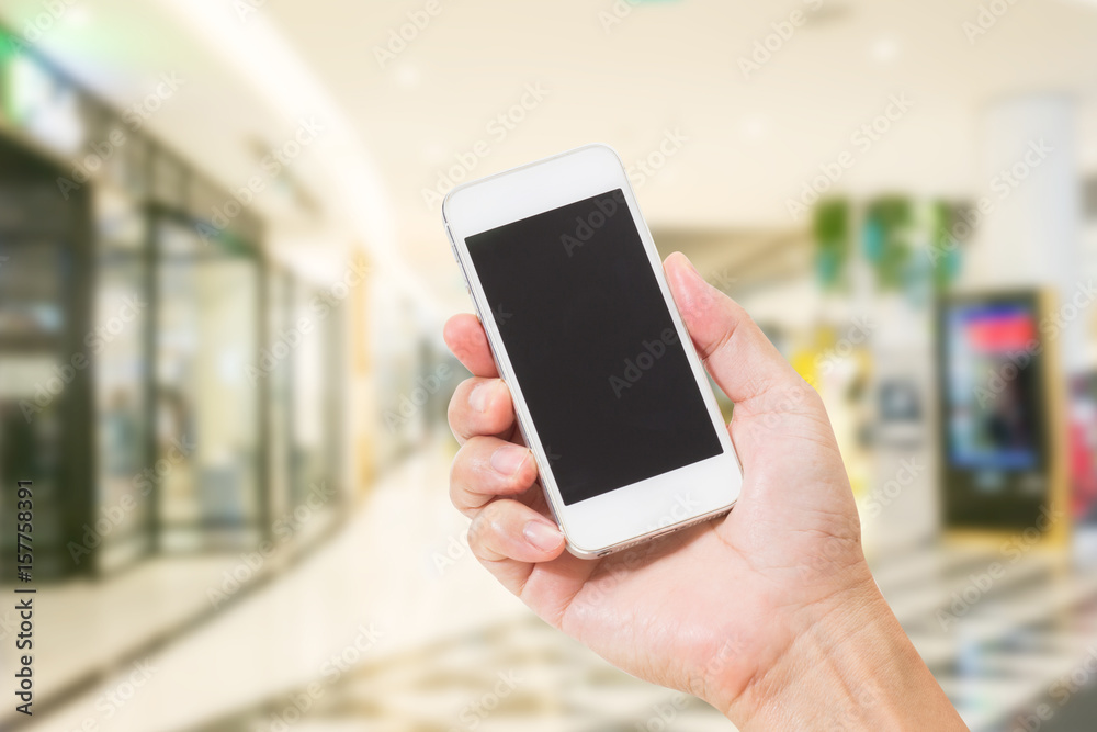 Hands holding mobile phone with blurred image of shopping mall Hands holding mobile phone with blurred image of shopping mall