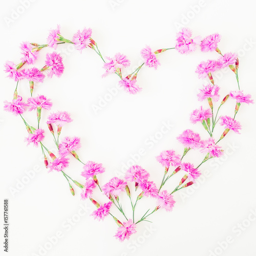 Love symbol made of pink flowers on white background. Flat lay, top view.