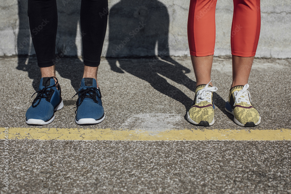 Legs of sportsman and sportswoman standing on concrete.