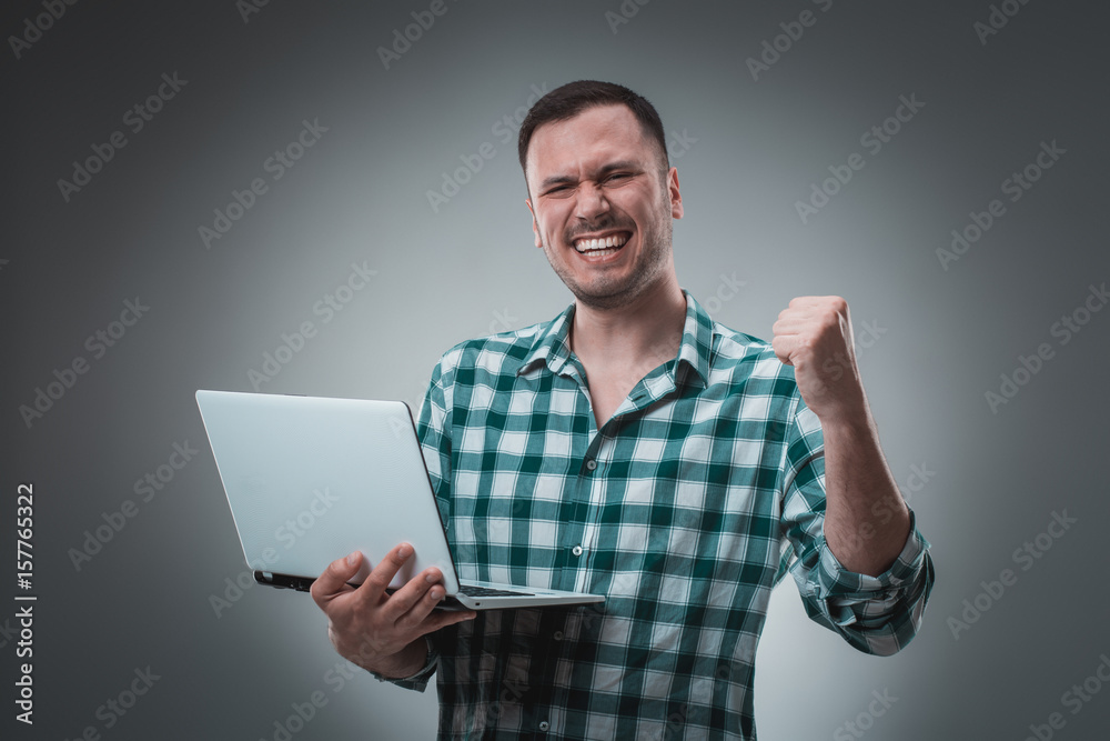 Portrait of young handsome man using laptop, wearing plaid shirt Portrait of young handsome man using laptop, wearing plaid shirt