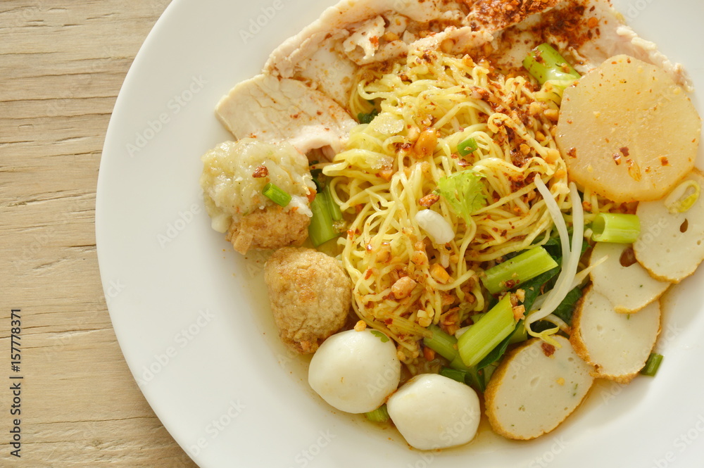 dried spicy Chinese egg noodles topping fish and shrimp ball with slice boiled pork on plate dried spicy Chinese egg noodles topping fish and shrimp ball with slice boiled pork on plate