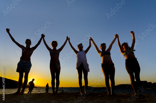 Group of People with Raised Arms backlit by the Sunset