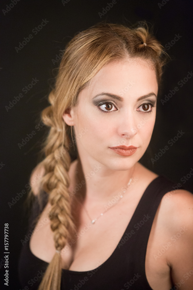 ritratto di bellissima ragazza bionda con la coda a treccia vestita di una canotta nera che guarda lontano - sfondo nero ritratto di bellissima ragazza bionda con la coda a treccia vestita di una canotta nera che guarda lontano - sfondo nero