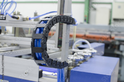 Industrial machine flexible power trak wire tray moving mechanism detail, selective focus copyspace background