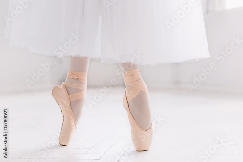 Young ballerina, closeup on legs and shoes, standing in pointe position.