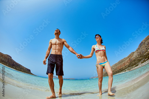 couple standing on the beach on a blue sea background © vitaliymateha