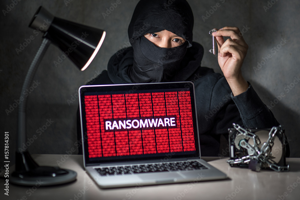 Hacker holding the key with laptop computer screen showing ransomware ...