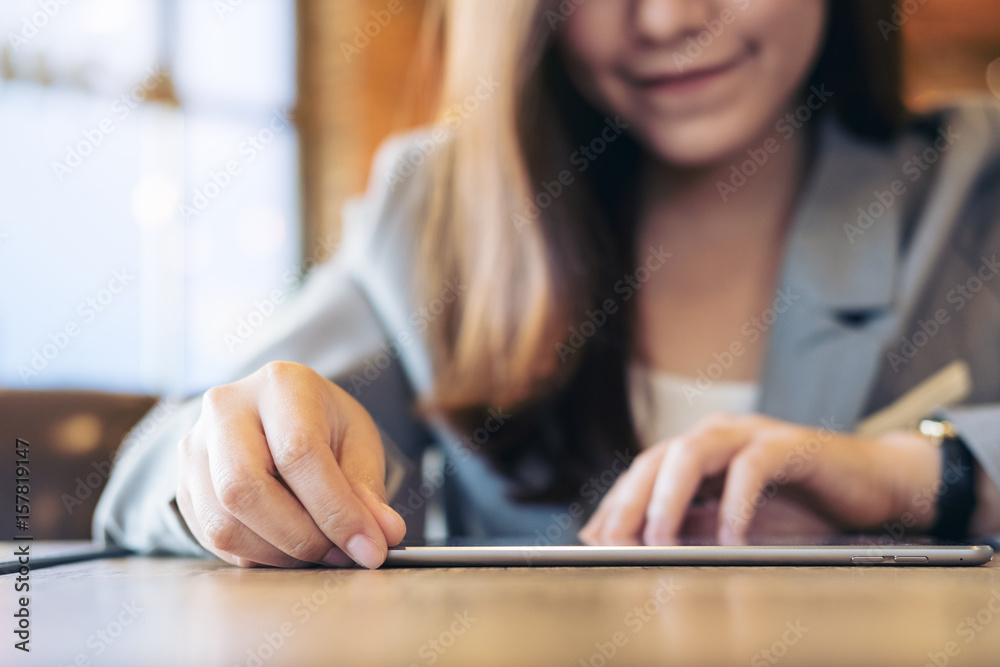 An Asian business woman looking and using tablet with blur background in cafe An Asian business woman looking and using tablet with blur background in cafe