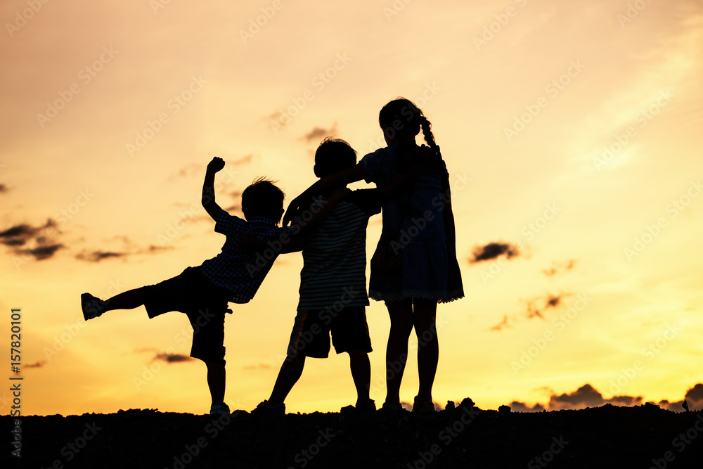 Silhouettes of group of children jumping high joyfully on sunset background