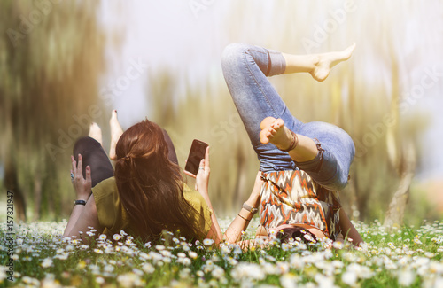 zwei junge frauen auf einer wiese - freundinnen lachen zusammen 