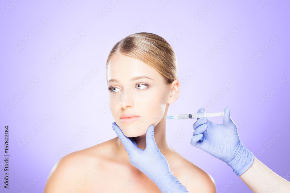 Doctor injecting in a beautiful face of a young woman. Plastic surgery concept. Doctor injecting in a beautiful face of a young woman. Plastic surgery concept.