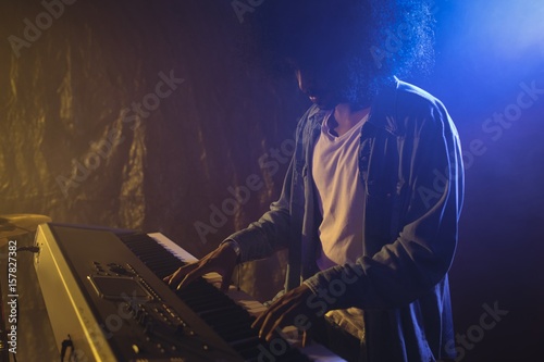 Male musician playing piano in illuminated nightclub