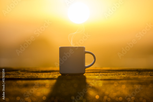 White Coffee cup in the morning time with sunrise.