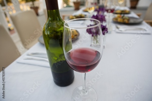Red wineglass and bottle on dining table at restaurant