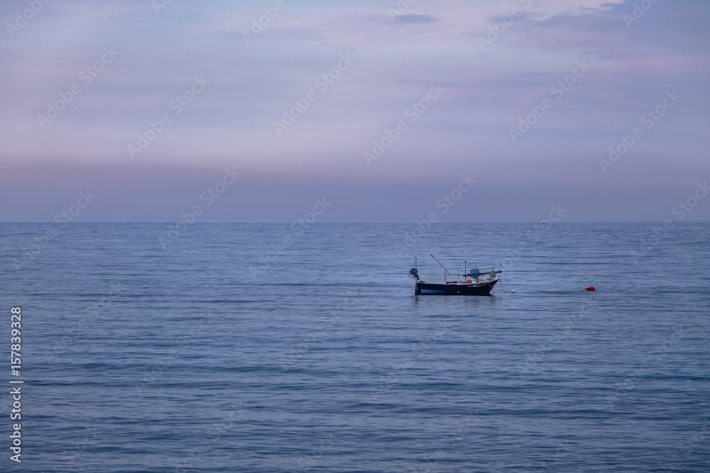 A boat in a Mediterranean beach of Ionian Sea at sunset - Bova Marina, Calabria, Italy