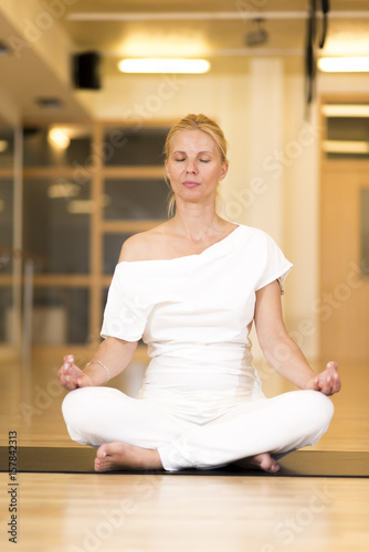 Young woman sitting cross legged on the floor doing yoga