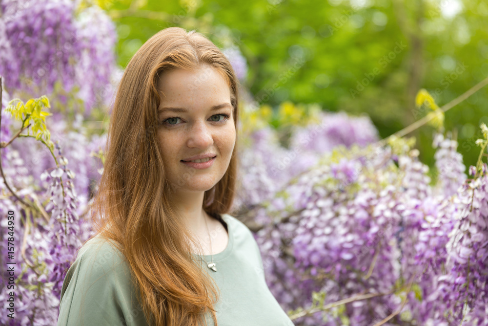 Natural beauty: red hair girl and freckles glow skin on the purple flowers background Natural beauty: red hair girl and freckles glow skin on the purple flowers background