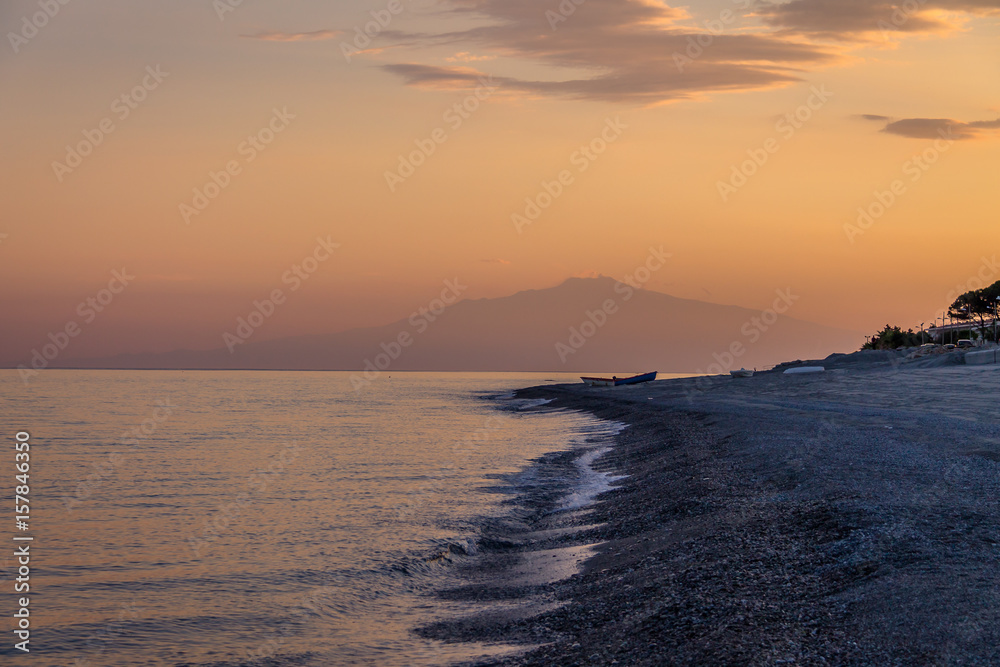 Sunset on a Mediterranean beach of Ionian Sea with Mount Etna Volcano on background - Bova Marina, Calabria, Italy