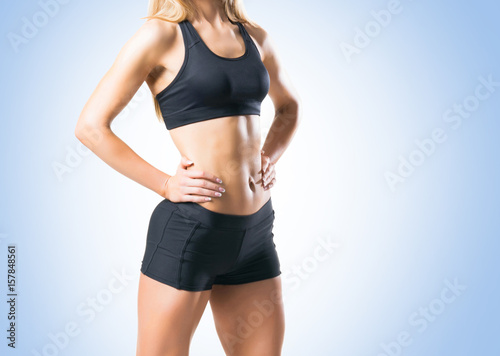 Fit, healthy and sporty woman in sportswear over blue background.