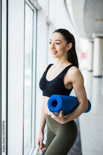 Beautiful woman with a yoga mat at the gym on panoramic windows © F8  \ Suport Ukraine
