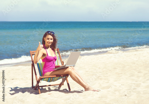 Young and beautiful woman working on a laptop on a beautiful beach. Freelance concept.