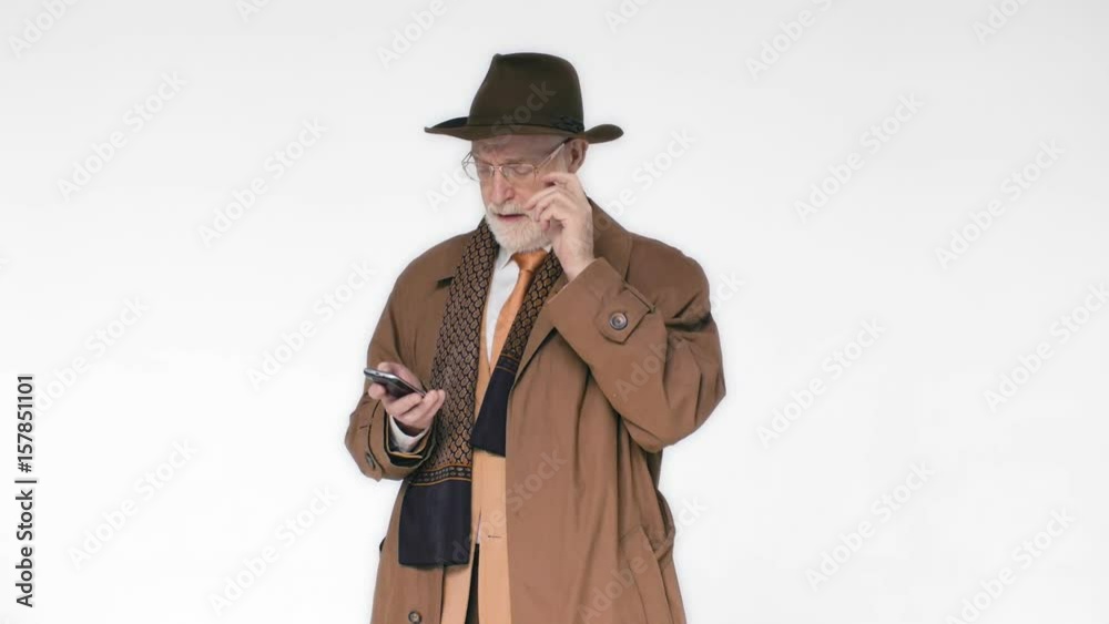An elderly man in a hat talking on the phone on white background. He's laughing and behaving in a relaxed way An elderly man in a hat talking on the phone on white background. He's laughing and behaving in a relaxed way