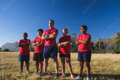 Trainer and kids standing with arms crossed in the boot camp