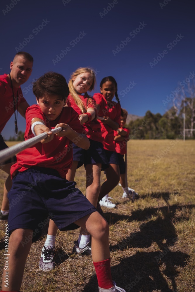 Trainer assisting kids in tug of war during obstacle Trainer assisting kids in tug of war during obstacle