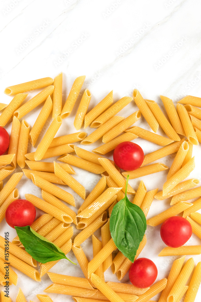 Penne rigate, cherry tomatoes, and basil leaves with copyspace