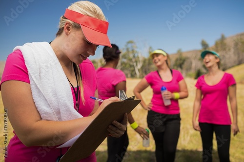 Female trainer writing on clipboard in the boot camp