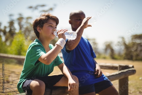 Boys drinking water after workout during obstacle course