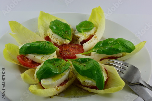 Basilicum on mozzerella on a tomato inside of chicory photo