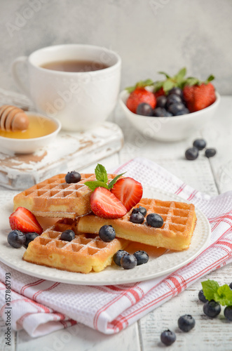 Waffles with fresh berries on rustic wooden background, selective focus