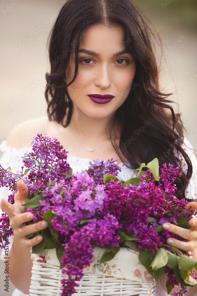 Beautiful girl outdoors. Pretty young woman with bouquet of lilac. Lady with flowers close up Beautiful girl outdoors. Pretty young woman with bouquet of lilac. Lady with flowers close up