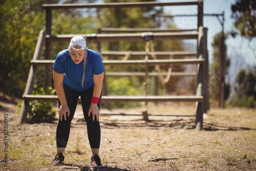 Tired woman bend down with hands on knees during obstacle course