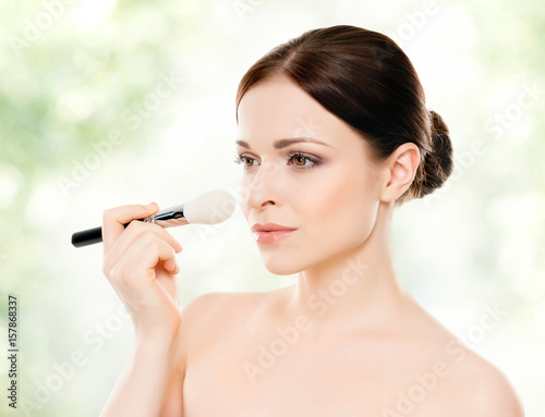 Close-up portrait of a beautiful woman  over green background. Healthcare  spa  makeup and face lifting concept.