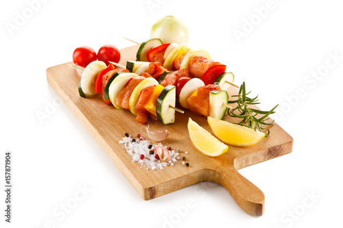 Raw kebabs on cutting board on white background