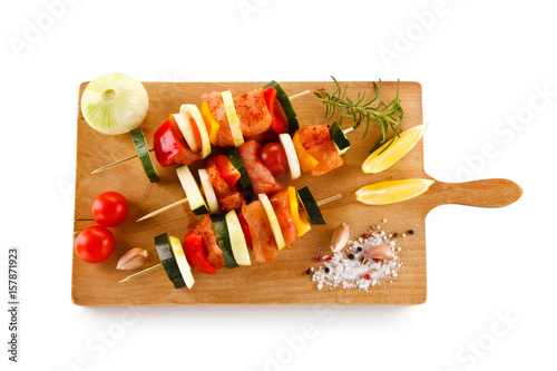 Raw kebabs on cutting board on white background