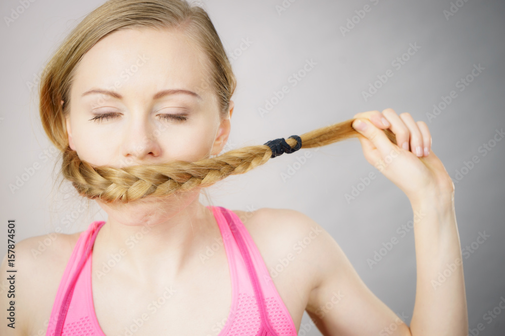 Woman covering her mouth with blonde braid Woman covering her mouth with blonde braid