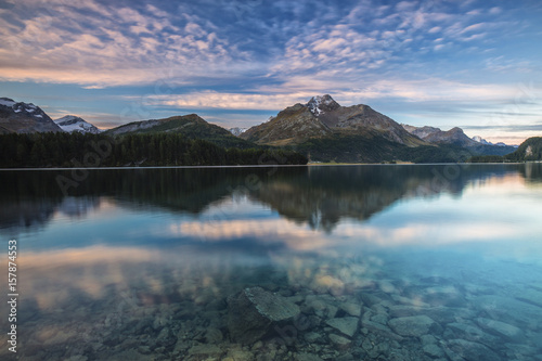 Pink sky at dawn illuminates the peaks reflected in Lake Sils Engadine Canton of GraubÃ¼nden Switzerland Europe