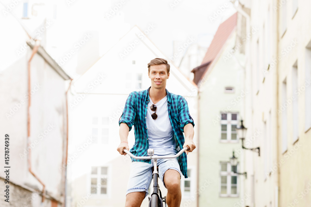 Handsome hipster riding a bicycle in old town. Traveling, holiday, vacation concept.