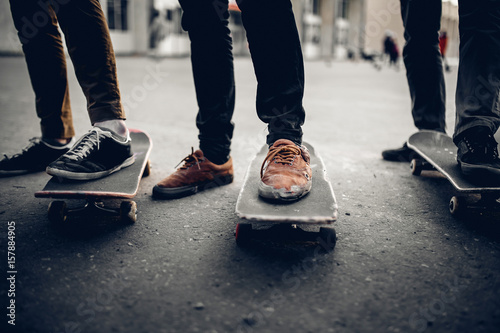 Group of friends skateboarders go in for sports on the street and ride skateboards, shoes in holes and abrasions. The concept is to lead the team to victory. Monochrome and high contrast. © Parilov