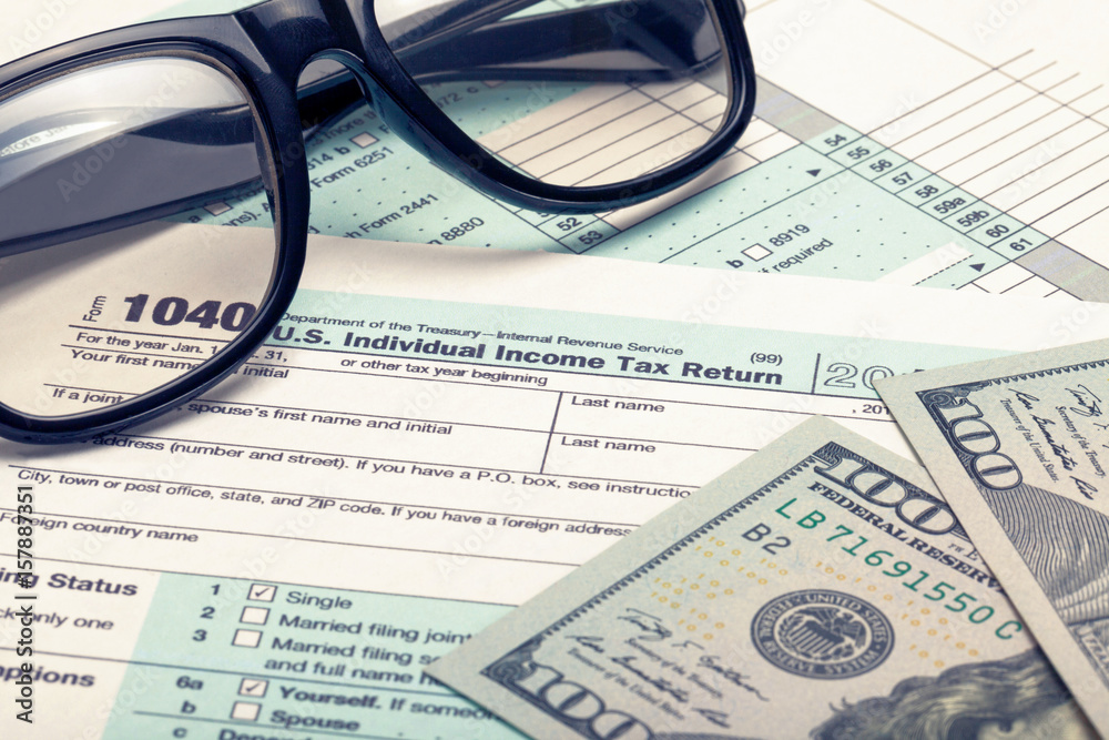 United States of America Tax Form 1040 with dollars and glasses. Filtered image: cross processed vintage effect. United States of America Tax Form 1040 with dollars and glasses. Filtered image: cross processed vintage effect.