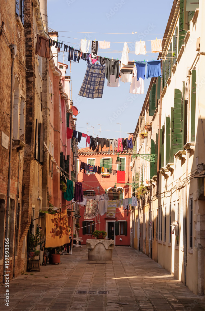 Traditional Italian street with clothes hanging out to dry between old houses, somewhere in Venice.