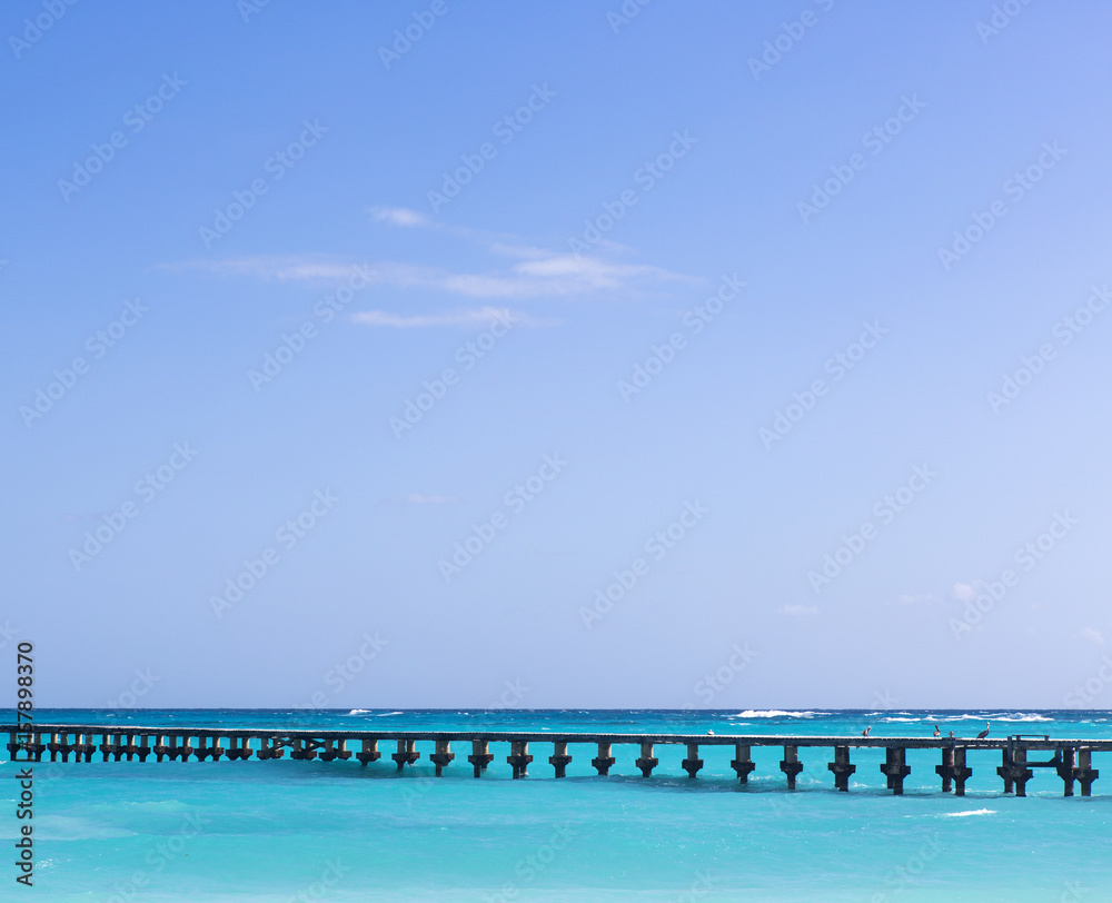Long wooden bridge over the turquoise waters. Shore of the Caribbean sea. Vacation concept image. Copy space.
