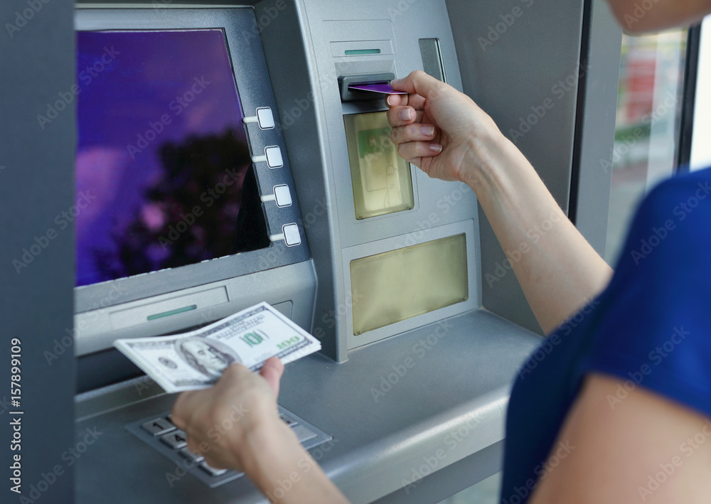 Woman taking money from a cash machine using credit card. Cash withdraw and finance concept Woman taking money from a cash machine using credit card. Cash withdraw and finance concept