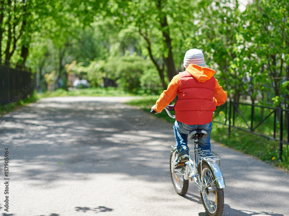 Naklejka premium Small boy ride bicycle in street park.
